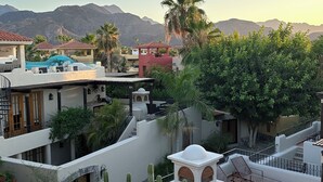 A courtyard with a pool, palm trees, and a view of mountains.