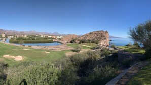 A golf course with a lake, mountains, and a building in the background.