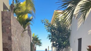 A stone-paved pathway leading to a building with a view of the sea.