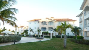 Un resort con un patio central, palmeras y un edificio grande con techo de tejas.