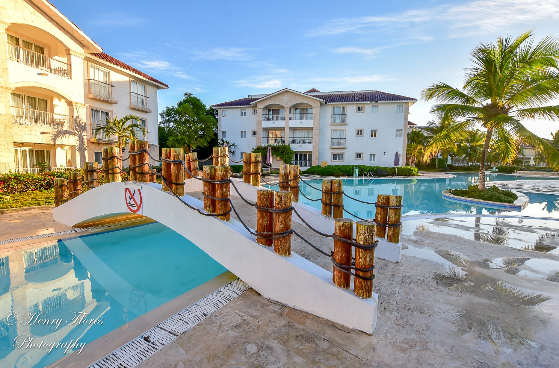 Un resort con piscina, barreras de madera y un edificio blanco con balcones.