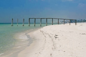 Une plage avec une jetée en bois qui s’avance dans l’eau.