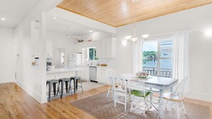 A spacious kitchen with white cabinetry, a dining area with a table and chairs, and a wooden ceiling. - ⭐Only 2 Blocks to Beach~Wraparound Porch + Top Deck~Inlet Rose (Rosemary Beach)