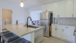 Een moderne keuken met een centraal eiland, roestvrijstalen apparatuur en witte kasten.