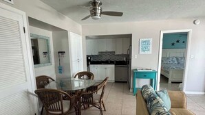 A compact living space with a dining area, kitchenette, and a sofa. - Beach & Pool Open! Beachfront View Every Room (Siesta Key)