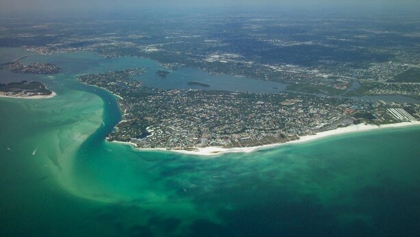 An aerial view of a coastal city with a large bay, a beach, and a dense urban area. - Beach & Pool Open! Beachfront View Every Room (Siesta Key)