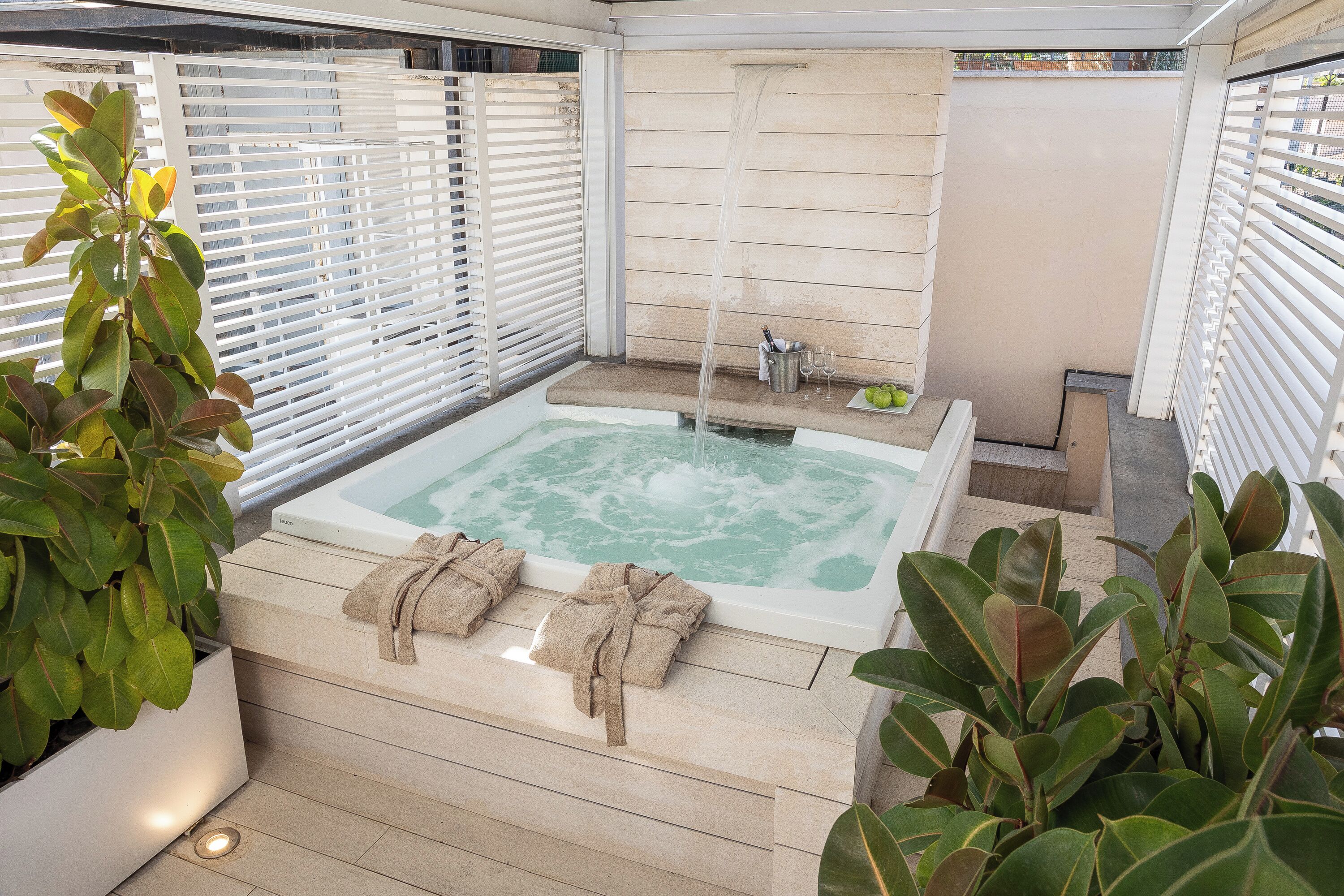 A spa area with a hot tub, towels, and potted plants.