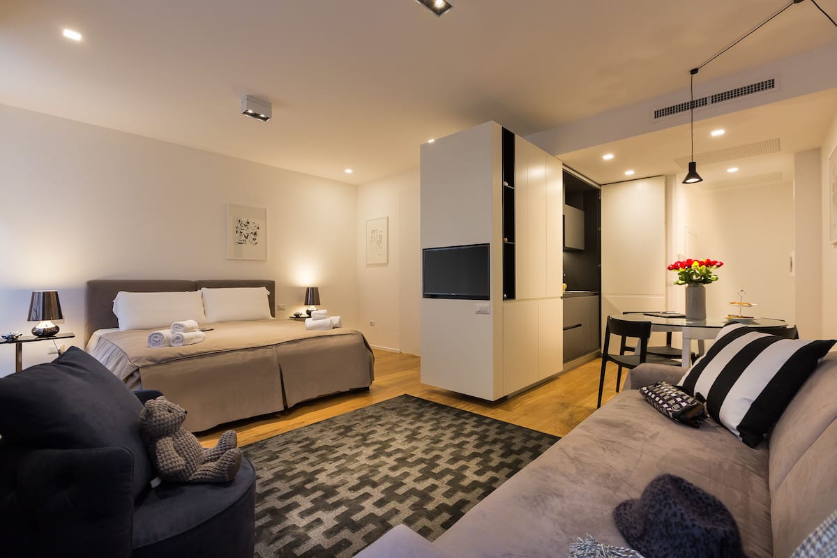 A modern, well-lit bedroom with a bed, bedside tables, and a TV.
