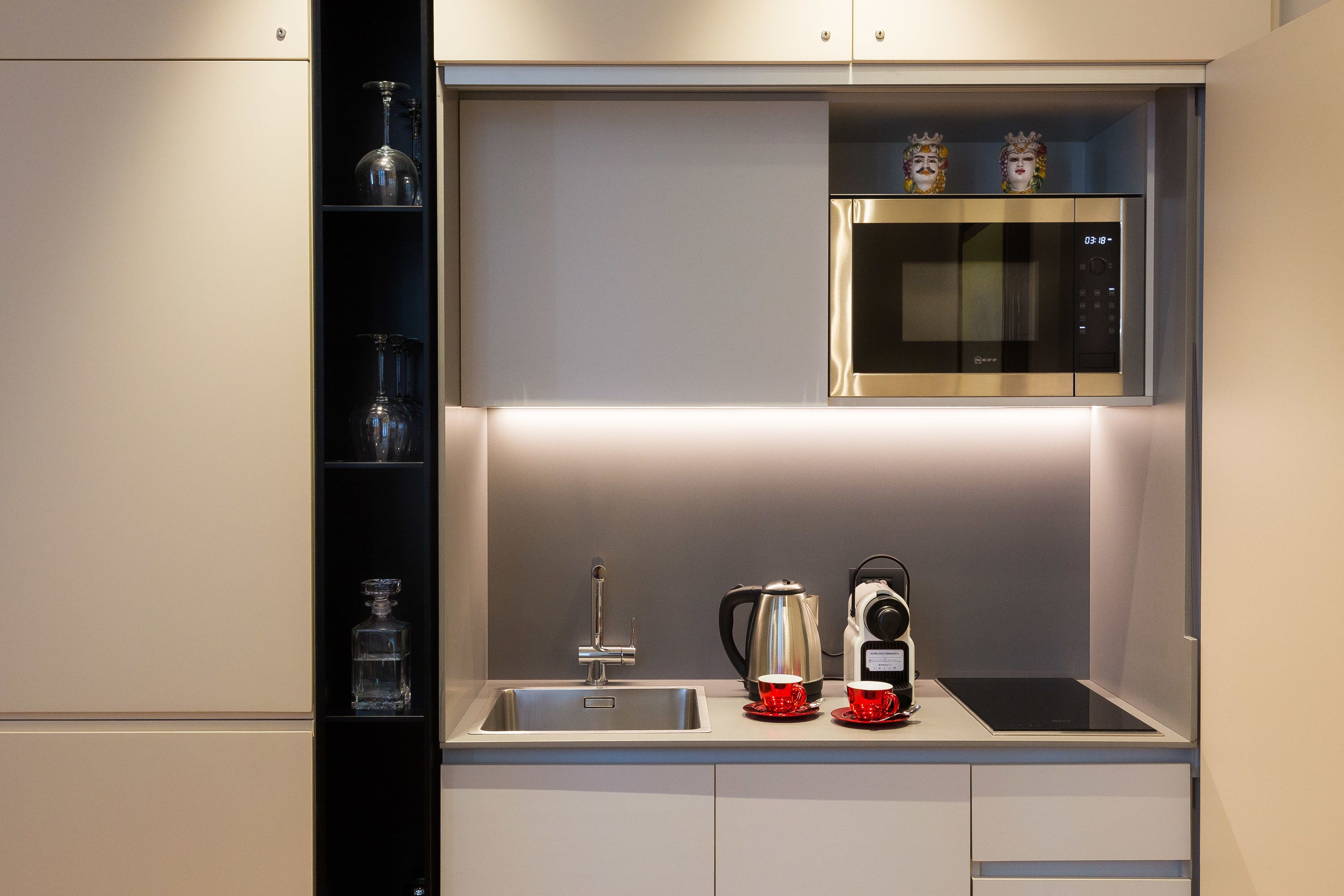 A modern kitchen with a built-in microwave, a coffee maker, and a kettle.