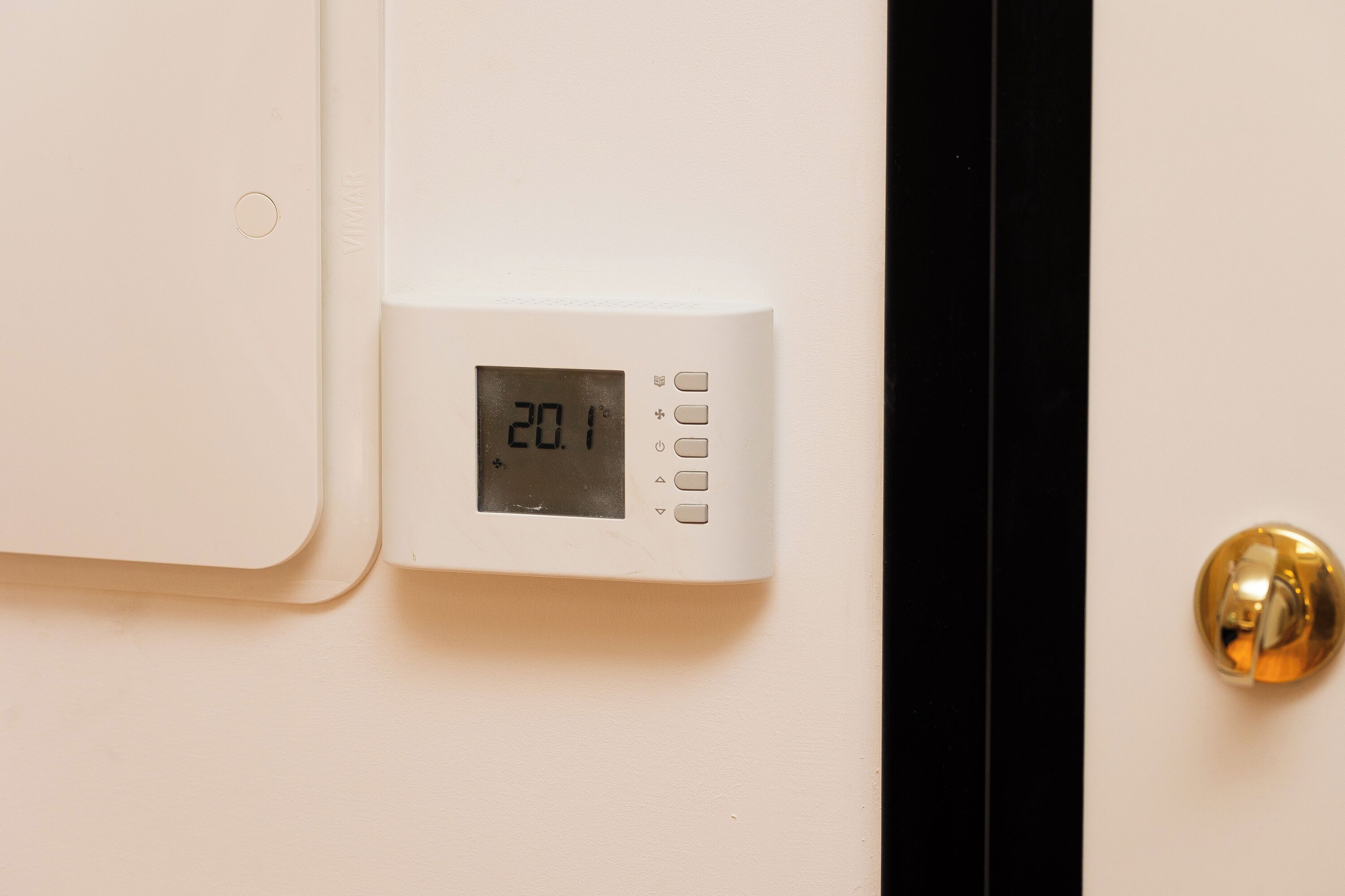 Termostato instalado en una pared con pantalla digital que muestra la temperatura.