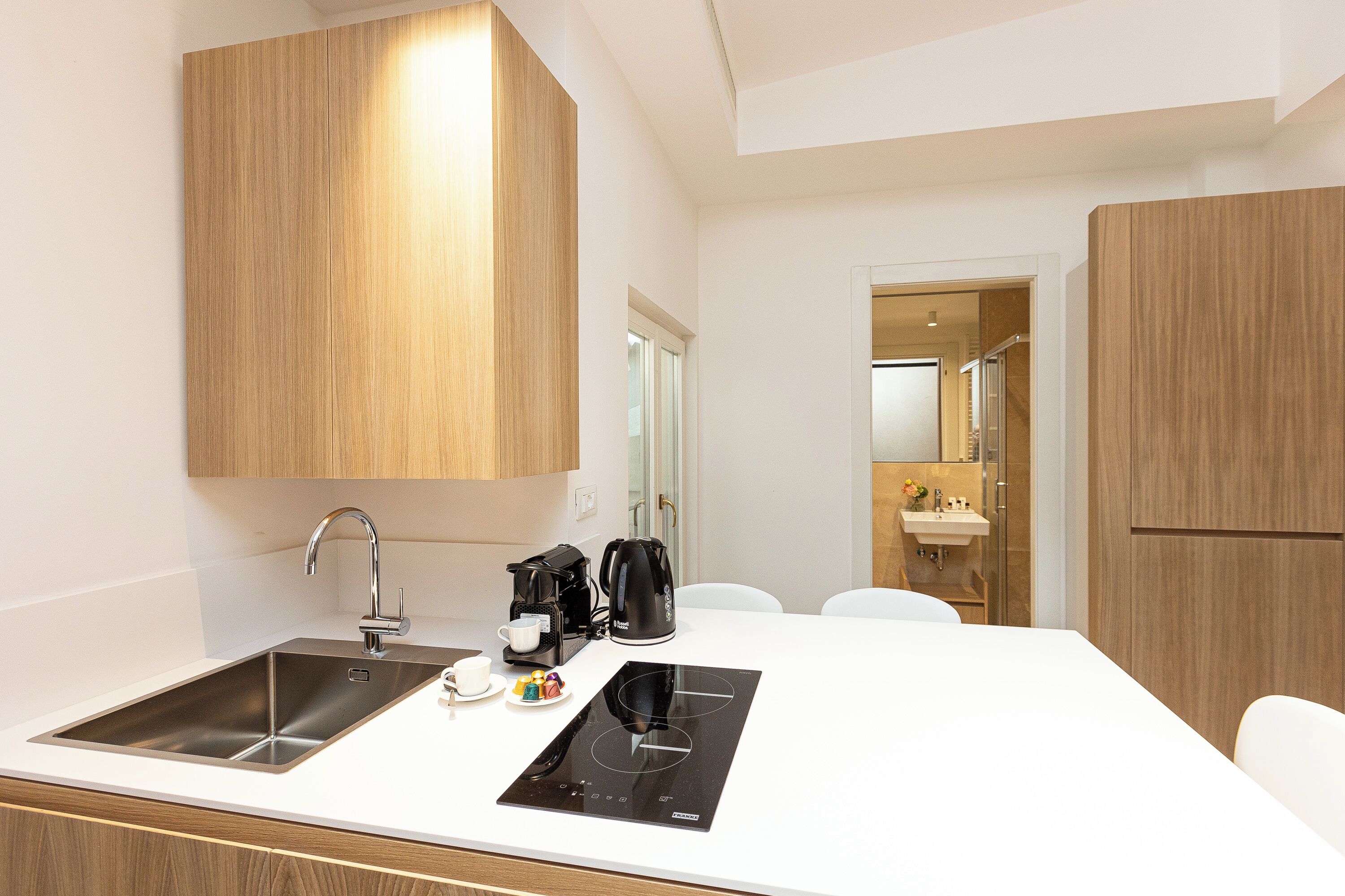A modern kitchen with a double sink, a coffee maker, and a built-in induction cooktop.