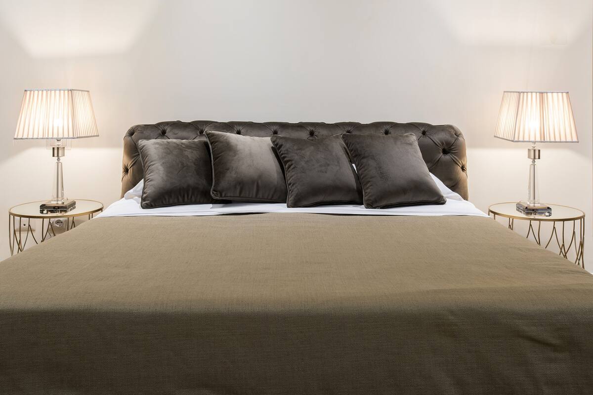 A bed with a tufted headboard, two bedside tables, and lamps.