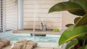 Een hottub met stromend water, omringd door houten wanden en een raam met luiken.