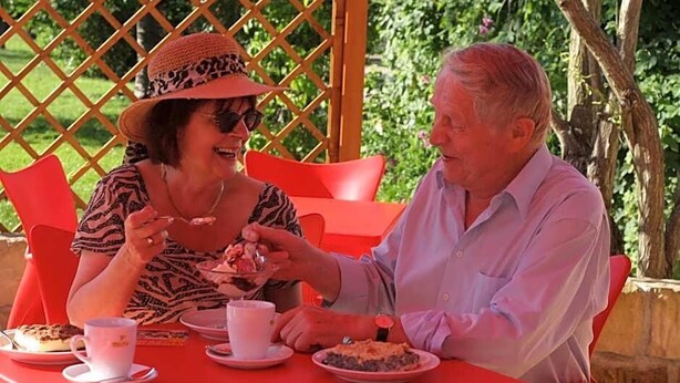Two people seated at a table with a lattice structure in the background.