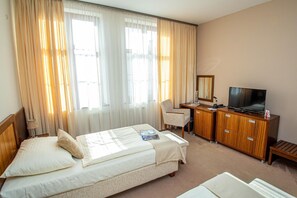 A hotel room with two beds, a desk with a TV, and a chair. - Hotel Academic (Zvolen)