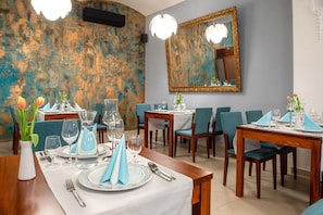 Comedor con mesas dispuestas para dos, servilletas azules y tulipanes en jarrones.