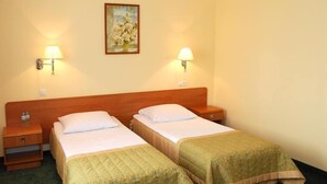 A hotel room with two single beds, a wooden headboard, bedside tables with lamps, and a painting on the wall. - Hotel U Witaszka (Czosnów)