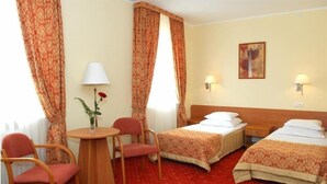 A hotel room with two beds, a small table with a chair, a lamp, and a painting on the wall. - Hotel U Witaszka (Czosnów)