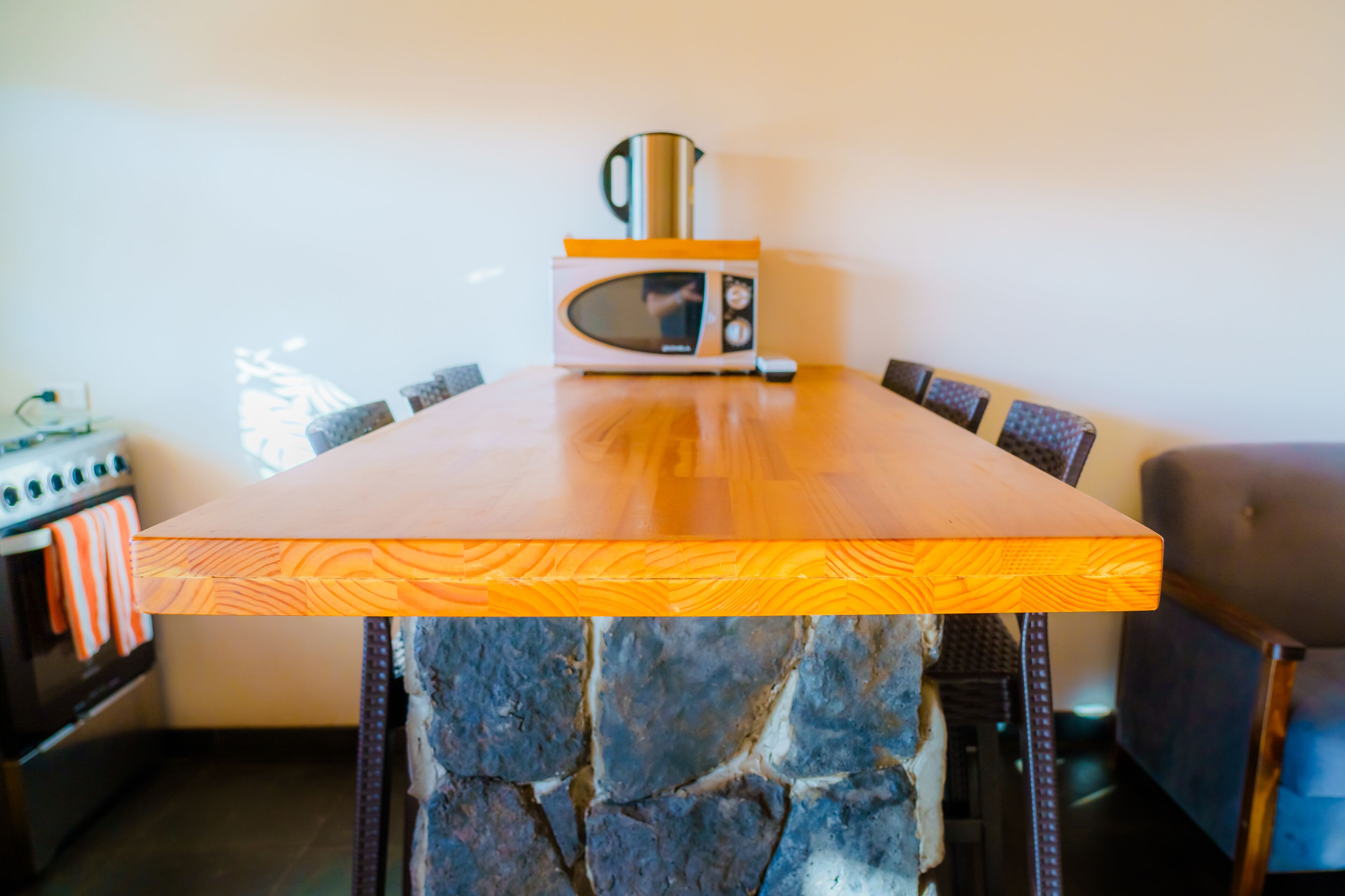 A wooden table with a stone base, a microwave, and a kettle on top.