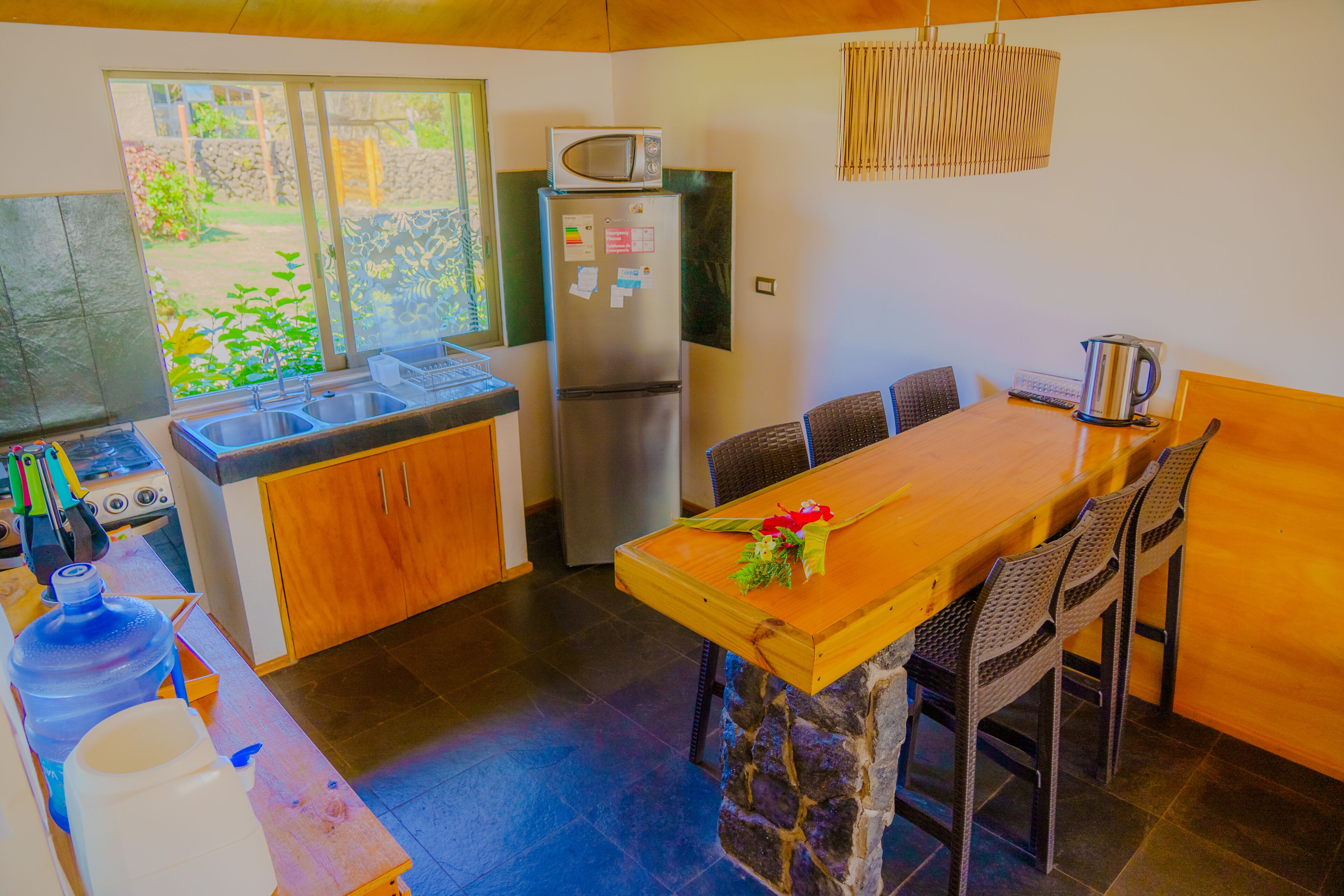 Una cocina compacta con refrigerador, microondas, pileta y una zona de comedor con mesa y sillas.