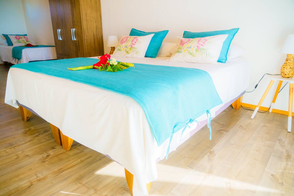 A hotel room with a large bed, wooden flooring, and a wooden wardrobe.