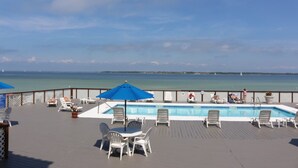 A poolside area with lounge chairs and umbrellas, overlooking a body of water. - Palm Beach Club by Surfside VR (Pensacola Beach)
