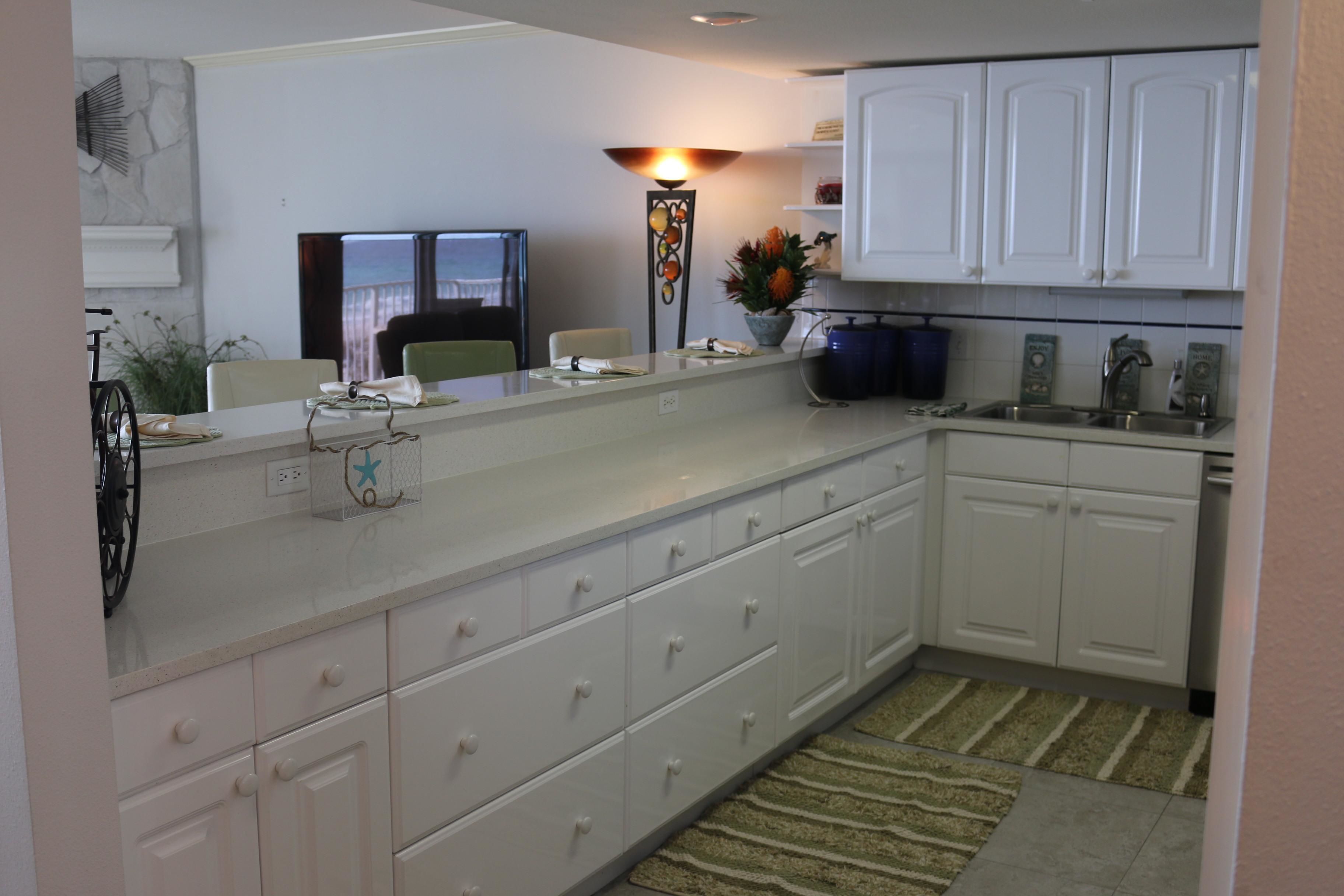 Una cocina moderna con armarios blancos, encimera de granito y lavavajillas integrado.