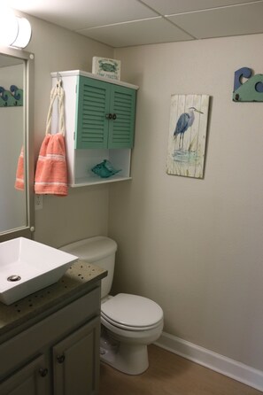 A bathroom with a white toilet, a white sink, a green cabinet, and a towel hanging on the wall.