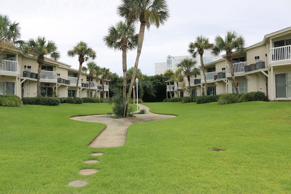 A hotel with a symmetrical layout, featuring multiple balconies and palm trees.