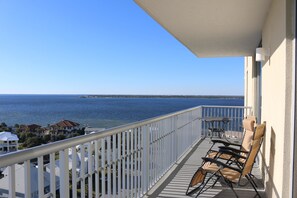 Un balcon donnant sur la mer, une balustrade blanche et deux chaises.