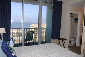 Une chambre d’hôtel avec un lit, une chaise, une petite table, une vue sur la mer et une salle de bain.