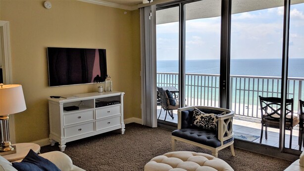 Habitació d'hotel amb un balcó gran, un taulell blanc, una televisió i vista a l'oceà.
