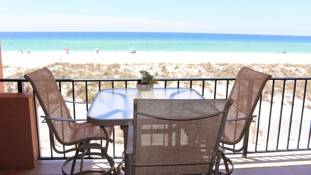 Un balcon avec une table et des chaises donnant sur une plage.