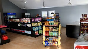 Un supermercado con estantes llenos de aperitivos, bebidas y una sección refrigerada.
