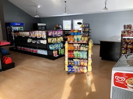 Un supermercado con estantes llenos de aperitivos, bebidas y una sección refrigerada.