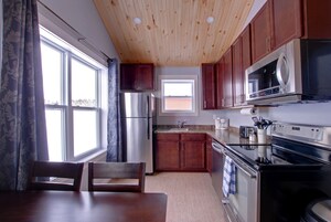 Una cocina con armarios de madera, electrodomésticos de acero inoxidable y un ventanal con cortinas.
