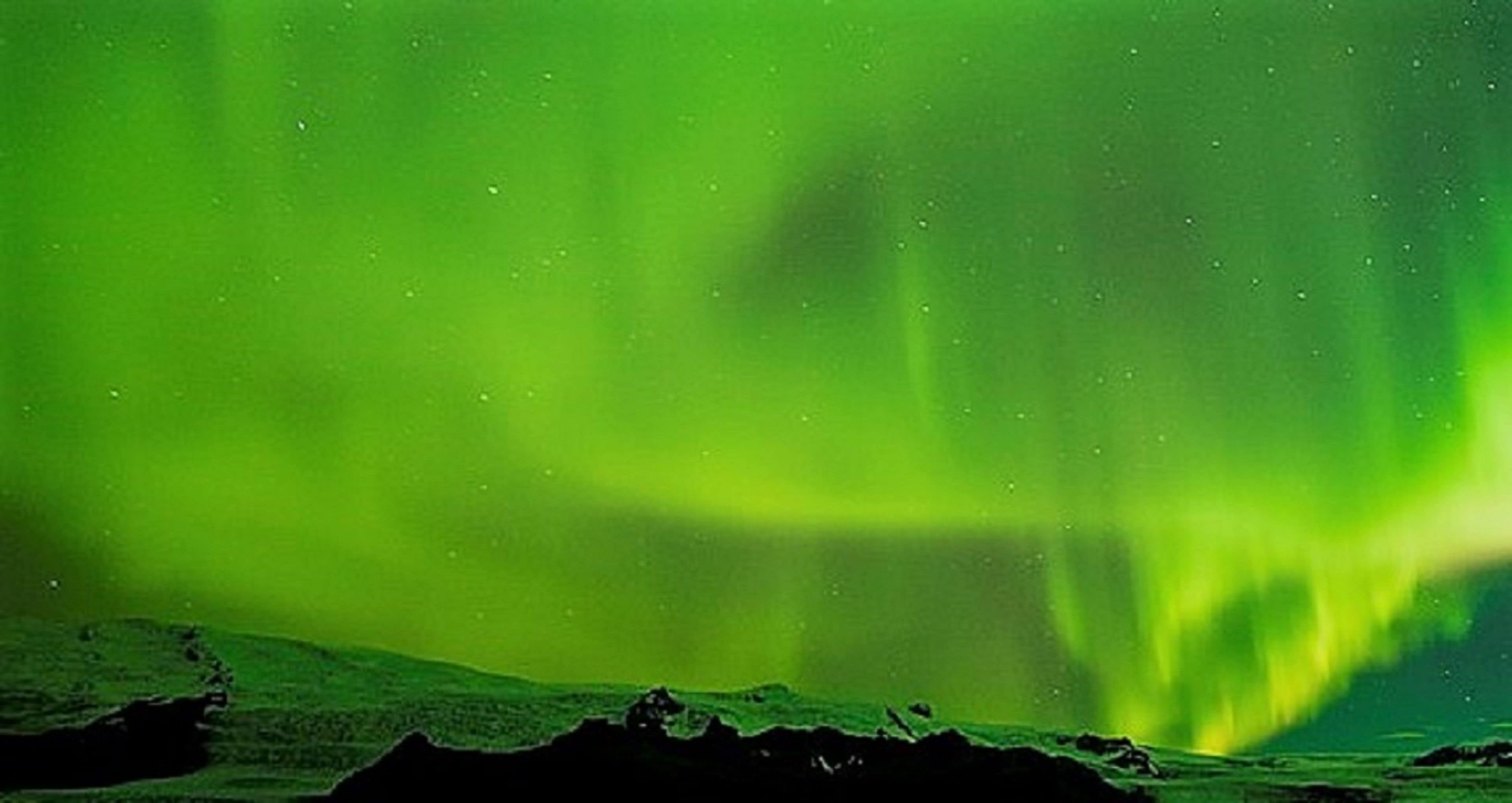 Una vista de las auroras boreales sobre un paisaje rocoso.