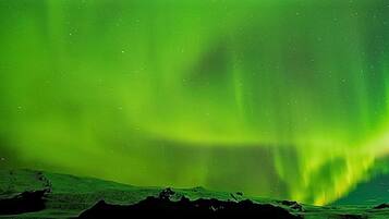 Una vista de las auroras boreales sobre un paisaje rocoso.