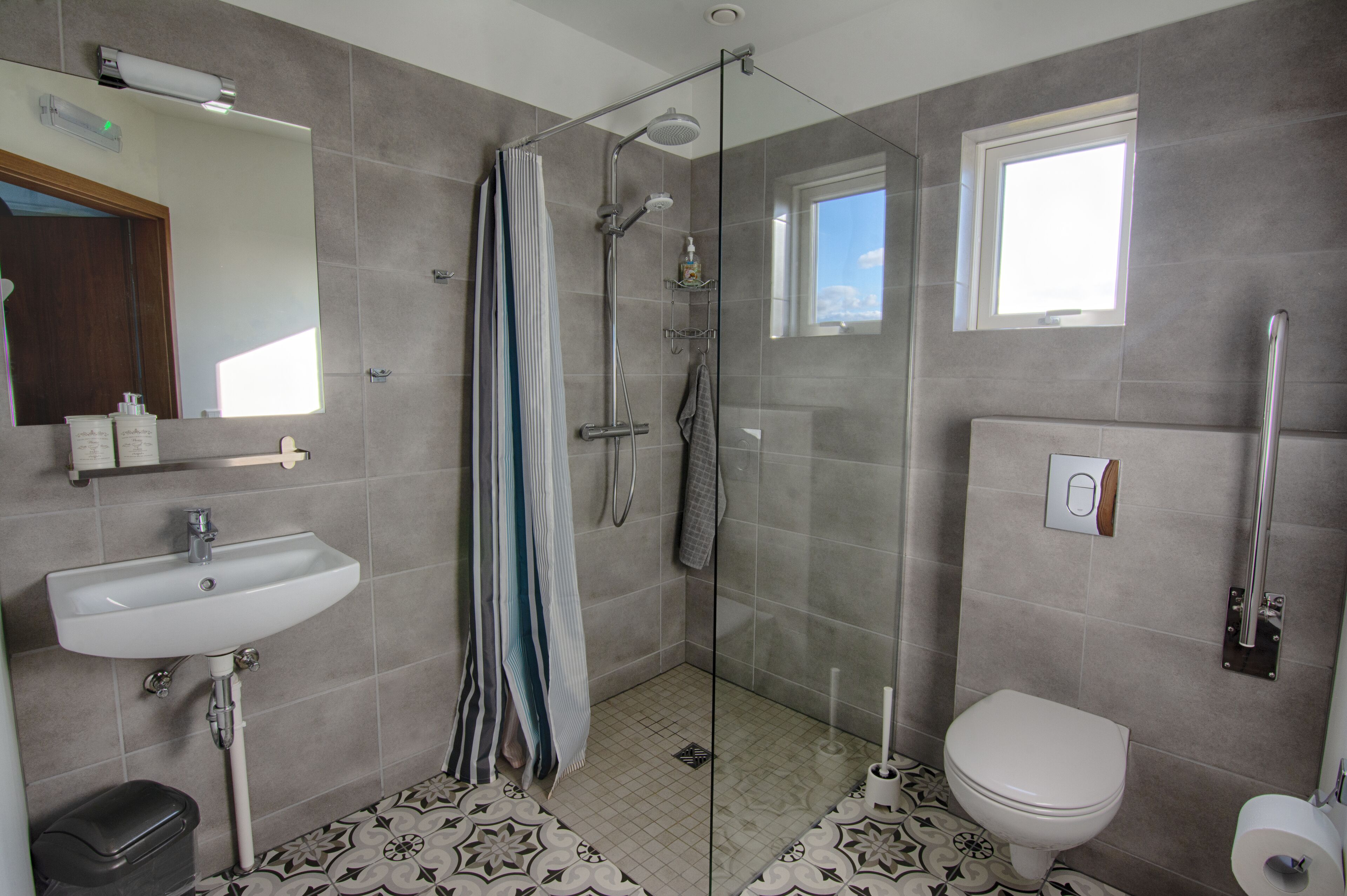 Een badkamer met douche, toilet, wastafel en spiegel.
