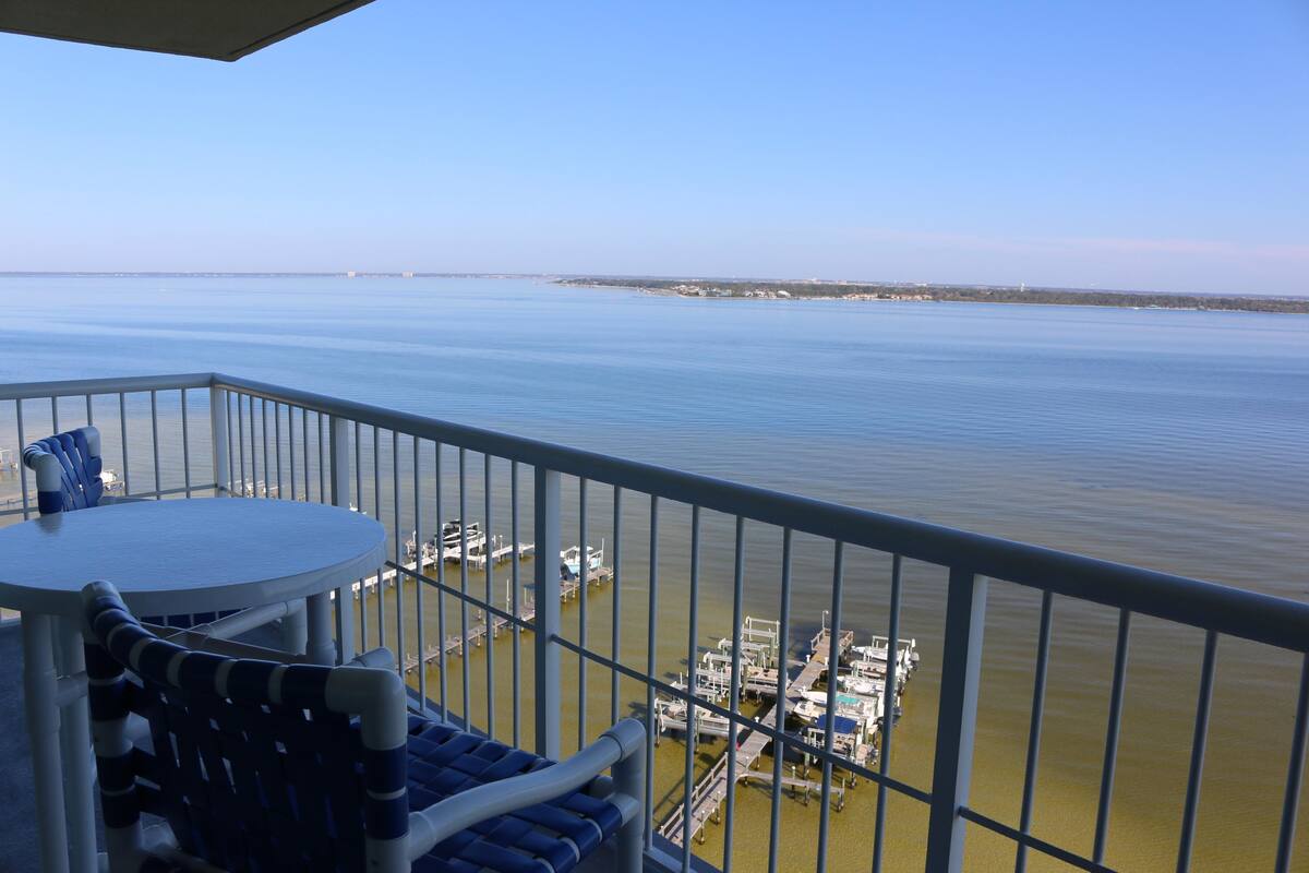A balcony with a view of calm water and docked boats.