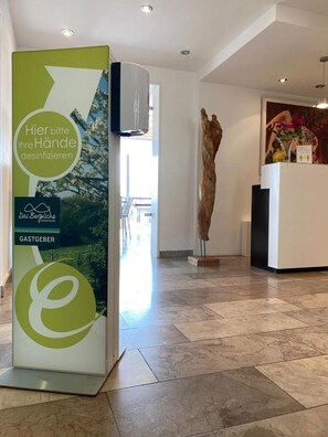 Un área de recepción con un letrero verde y blanco, una escultura de madera y un mostrador de recepción.