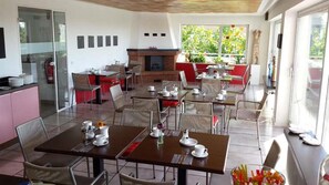 Un comedor con mesas dispuestas para el desayuno, una chimenea y vistas al exterior.