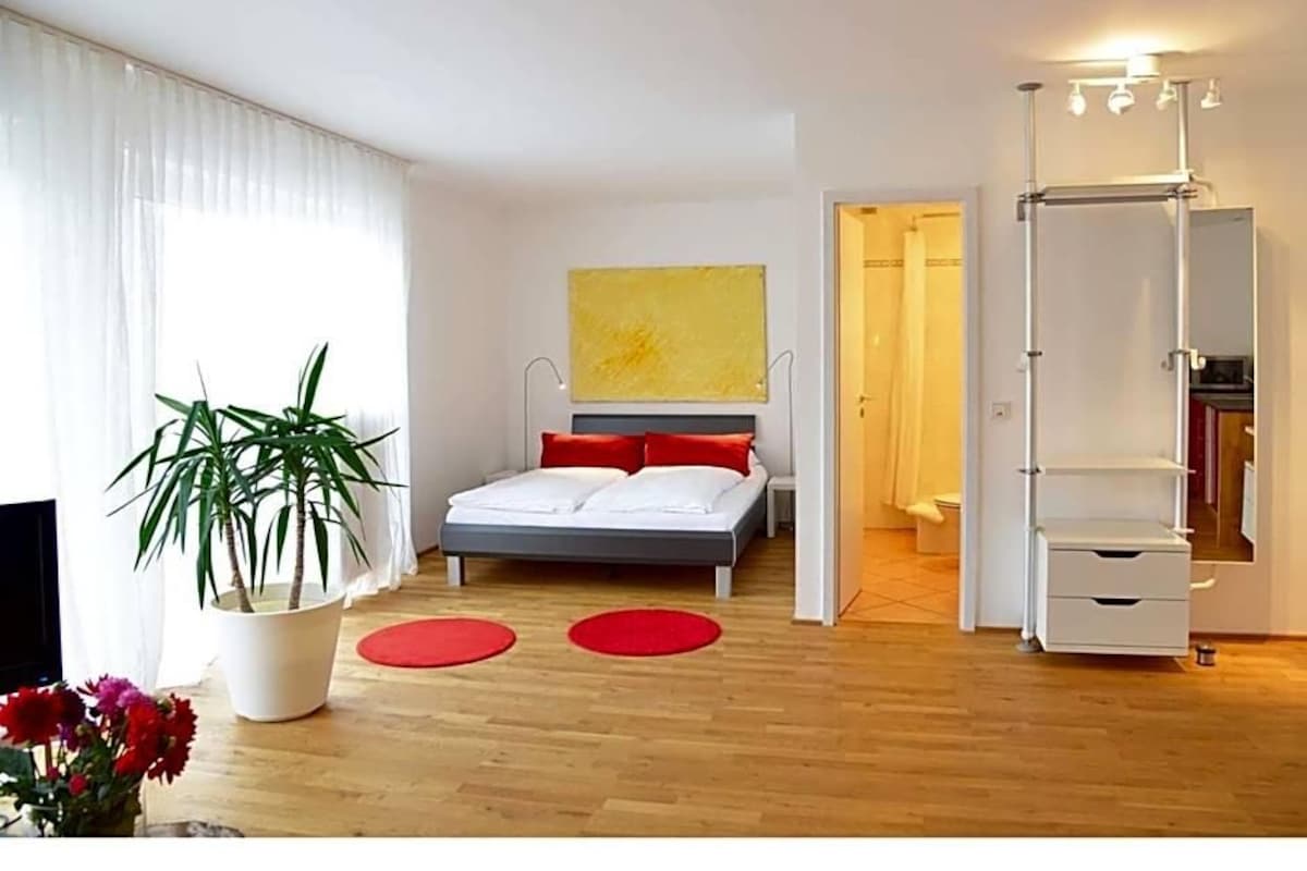 Un dormitorio moderno con una cama, una planta en maceta y un espejo.