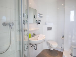 Un baño moderno con cabina de ducha de vidrio, un lavamanos blanco y un inodoro.