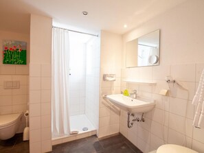 A modern bathroom with a shower, toilet, and sink.