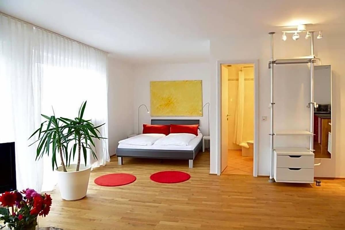 A modern bedroom with a bed, a potted plant, and a mirror.