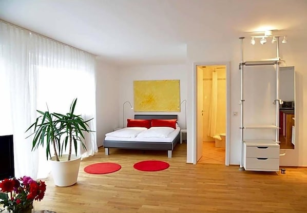 A modern bedroom with a bed, a potted plant, and a mirror.