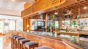 A bar area with a marble countertop, wooden stools, and a variety of bottles and glasses. - Hotel Martorell (Ses Salines)