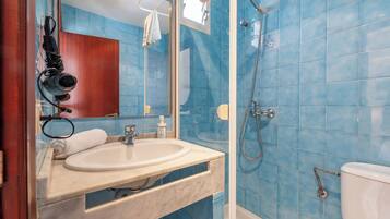 A bathroom with a sink, mirror, and shower.