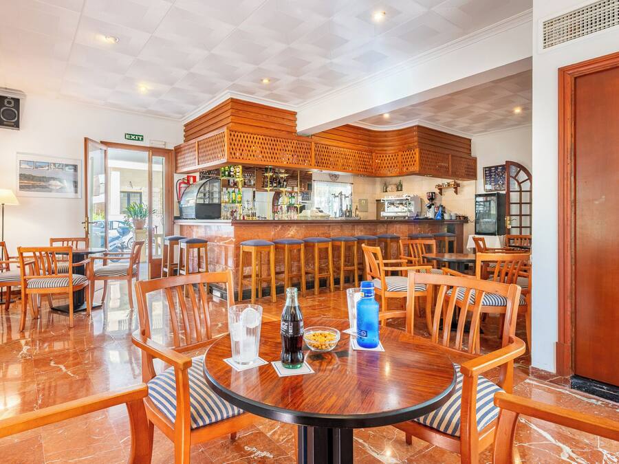 Un restaurant amb zona de bar, mobles de fusta i un terra de marbre.